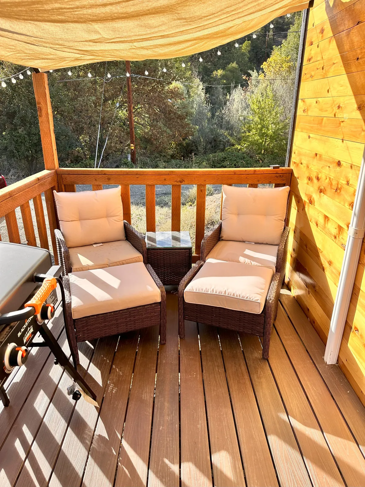 This image features two wicker chairs and a small table arranged outside, offering a cozy spot to sit and take in the natural surroundings. The outdoor ambiance is inviting, suggesting a private space for couples to enjoy the fresh air, perhaps with a glass of wine in hand while watching the sun set or stargazing at night.